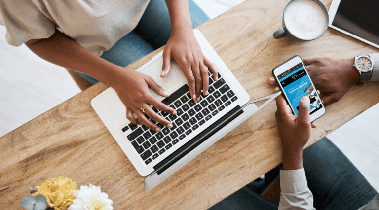 Website design services overhead view of woman typing on the computer in front of man holding a cell phone